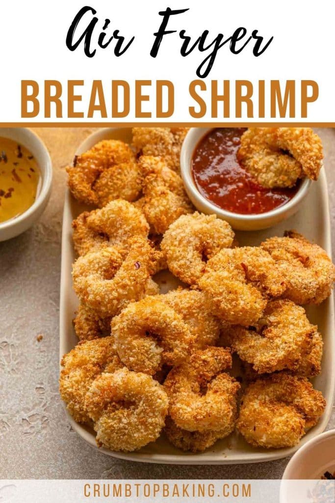 Pinterest image with breaded shrimp piled on a plate with a small bowl of seafood sauce.