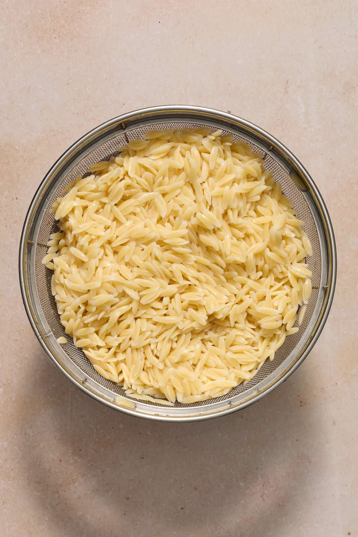 Cooked orzo in a colander.