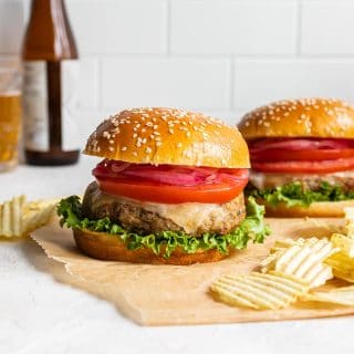 Air fryer turkey burgers arranged on a sheet of brown parchment paper with potato chips on the side.