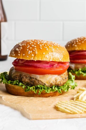 Air fryer turkey burgers arranged on a sheet of brown parchment paper with potato chips on the side.