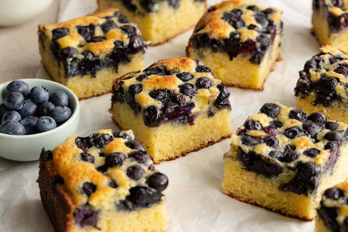 Squares of blueberry cake on a sheet of parchment paper.