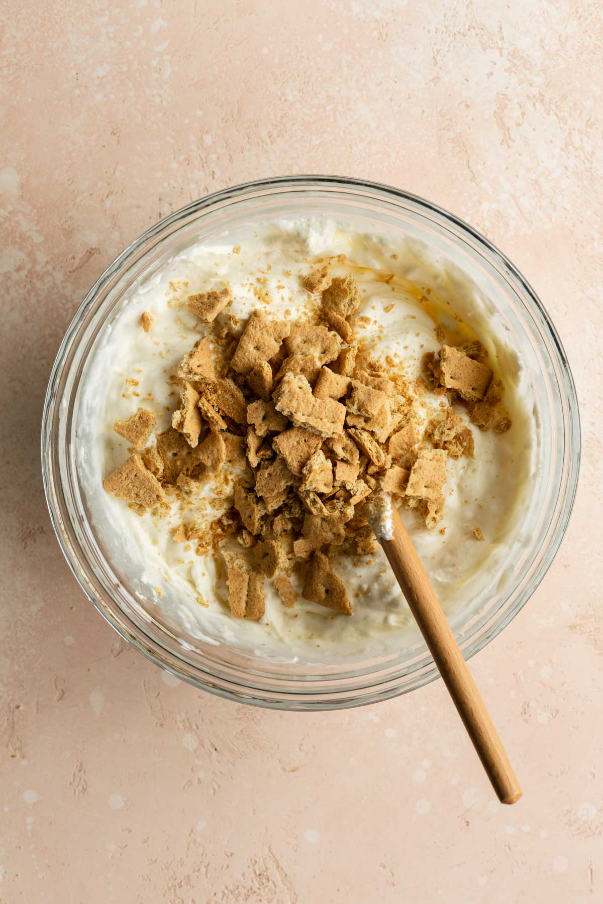 Chopped graham crackers added to the ice cream mixture in a glass bowl.