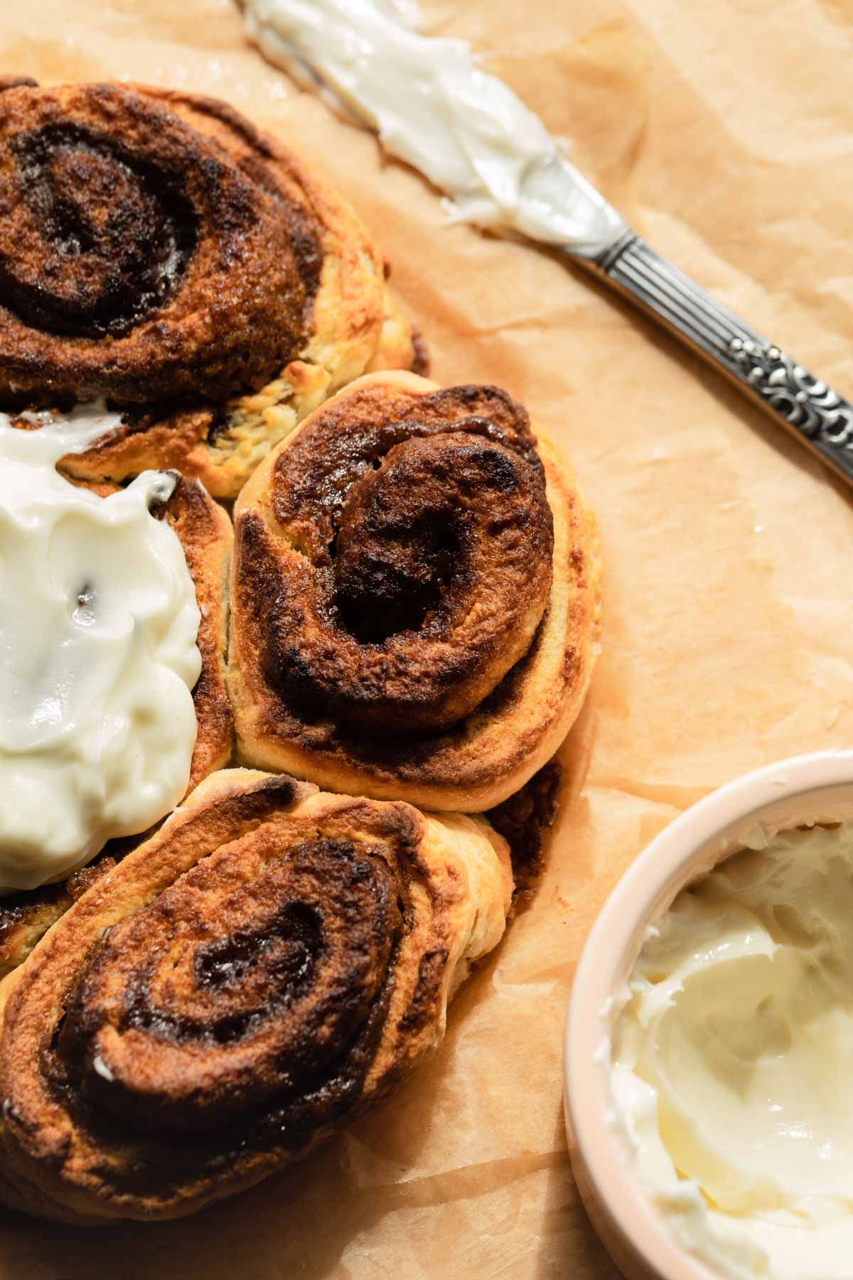 Overhead close up of cinnamon rolls on parchment paper.