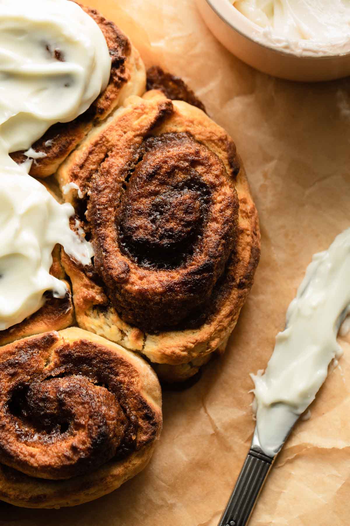 Close up of a cinnamon roll with a frosted knife on the side.