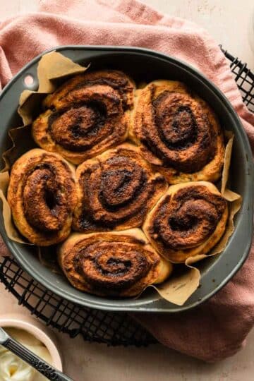 Overhead view of air fried cinnamon rolls in a round cake pan.