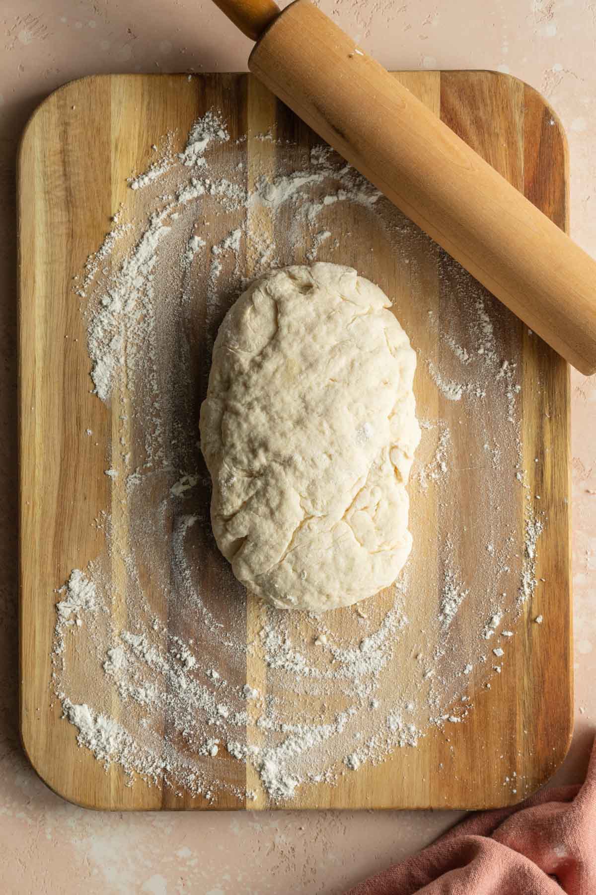 Cinnamon roll dough on a floured wooden surface.