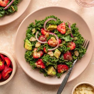 Strawberry kale salad on a pink plate.