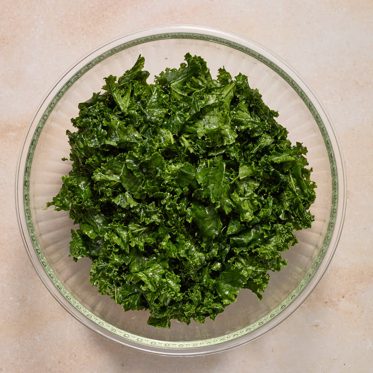 Massaged curly kale in a large glass bowl.