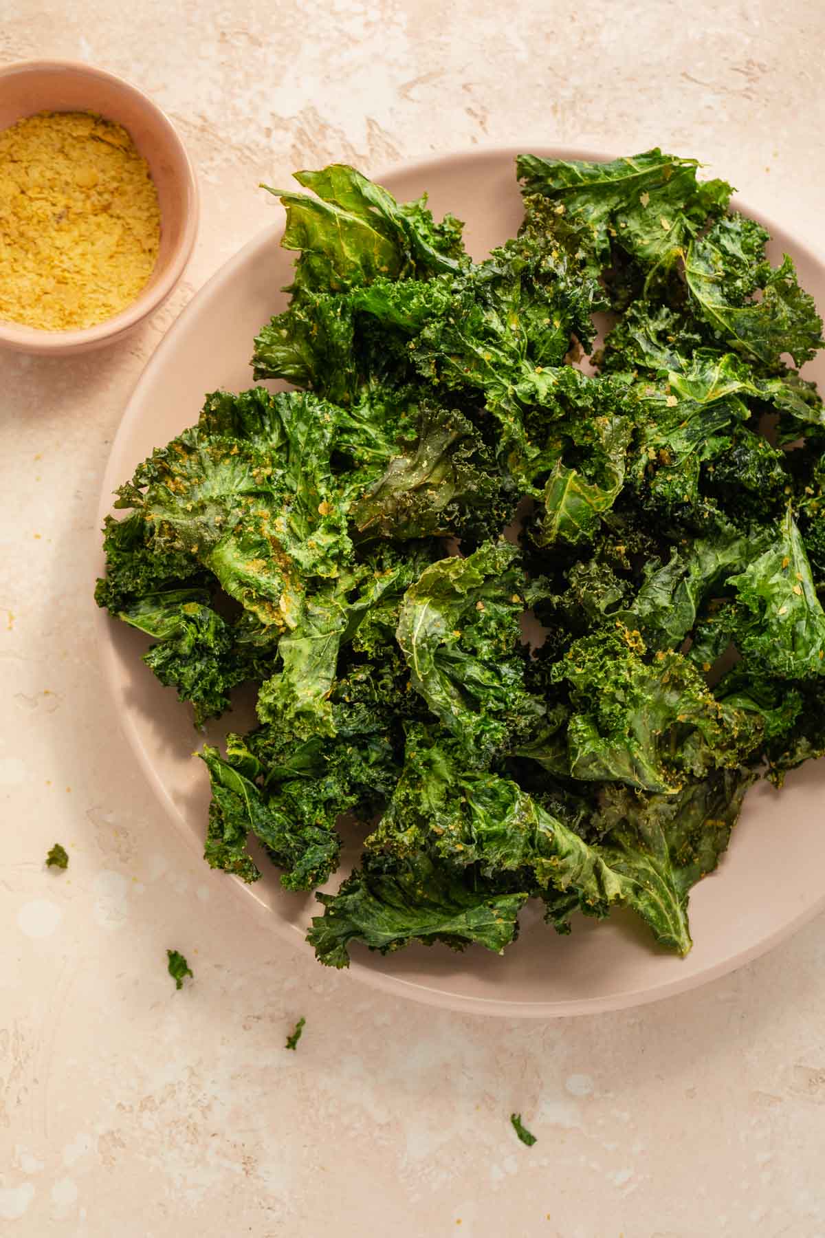 Overhead view of kale chips on a pink plate.