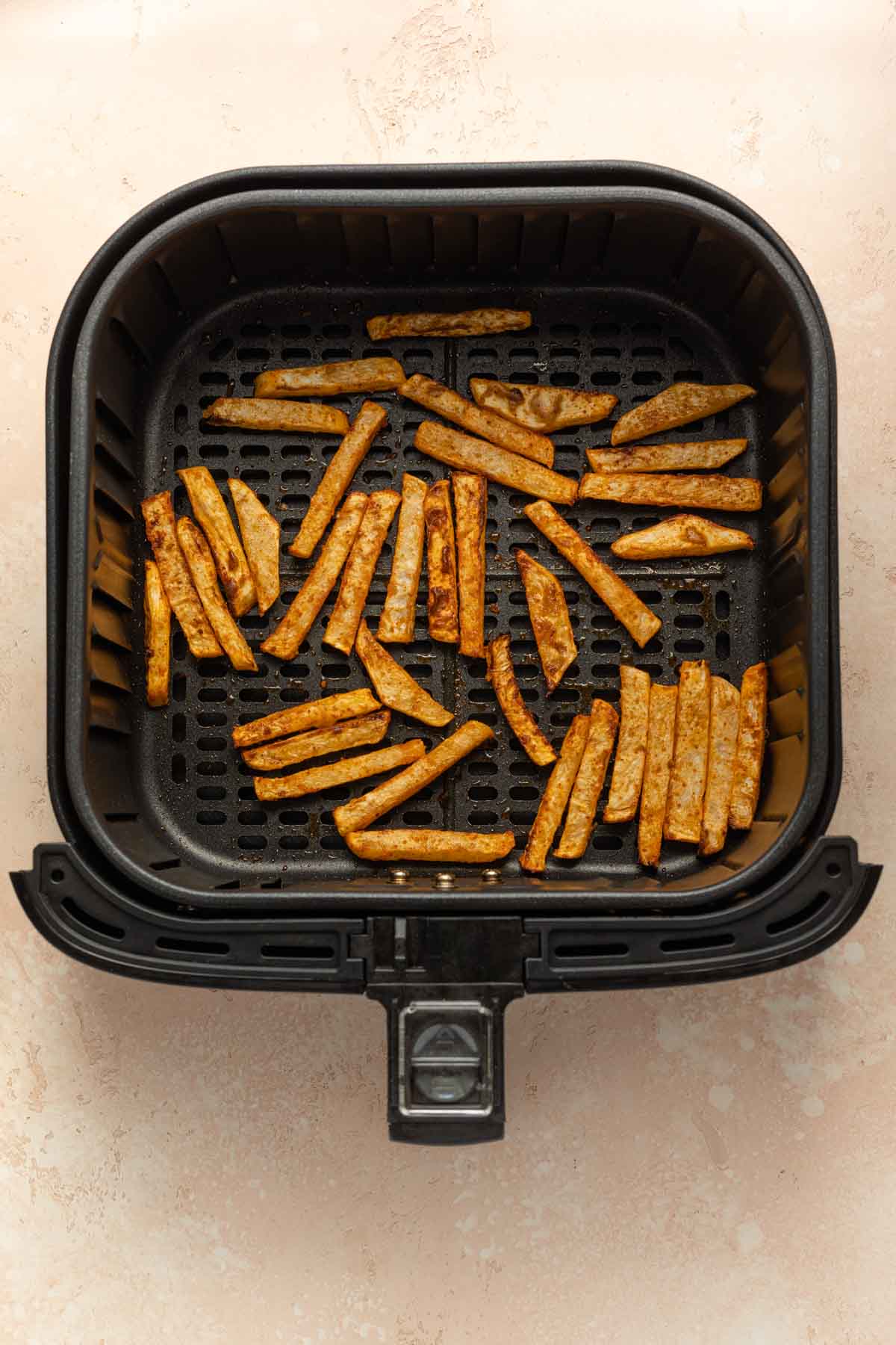 Air fried turnip fries in an air fryer basket.