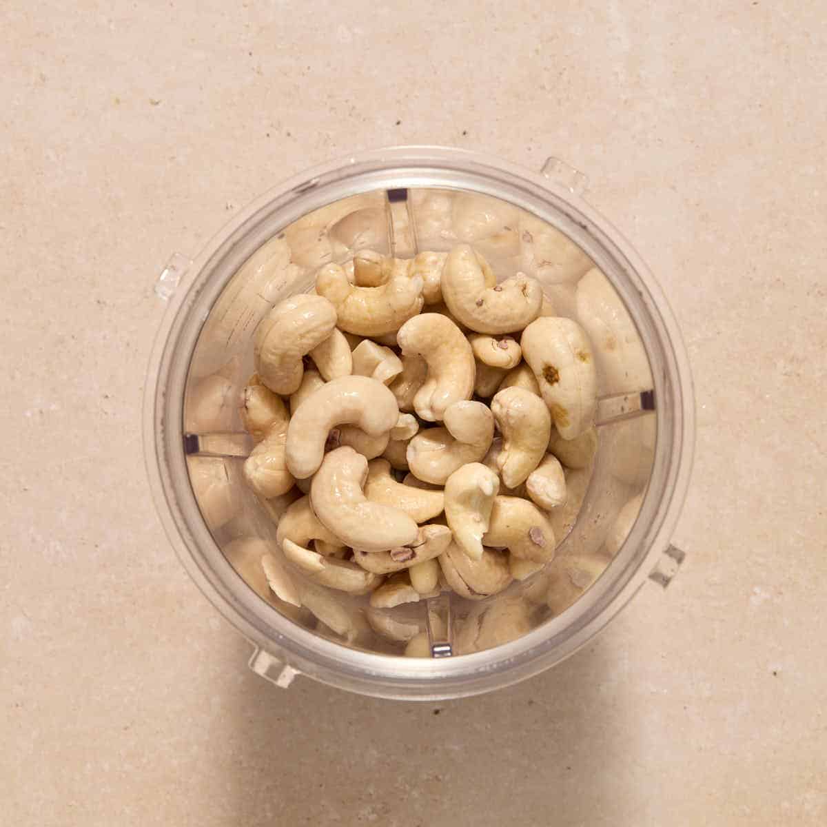 Softened cashews added to a smoothie cup blender.