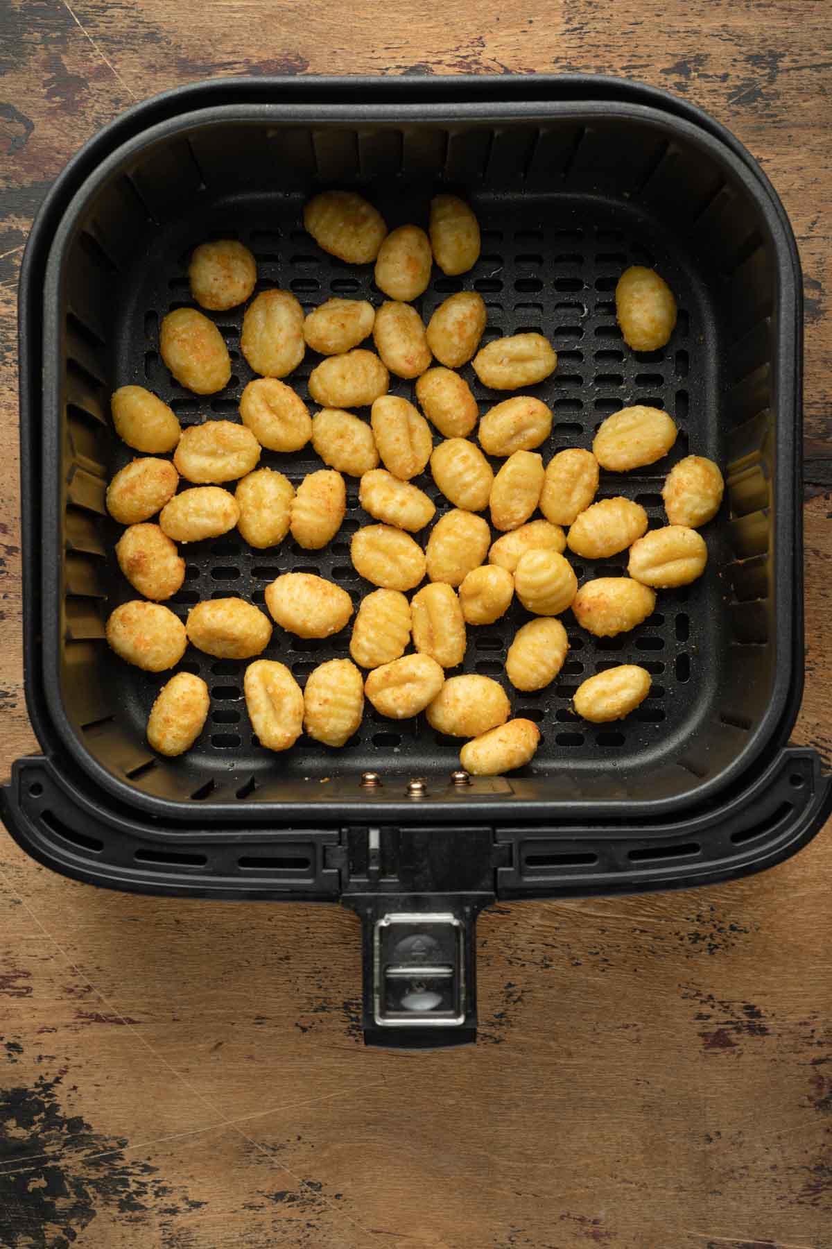 Air fried gnocchi in an air fryer basket.