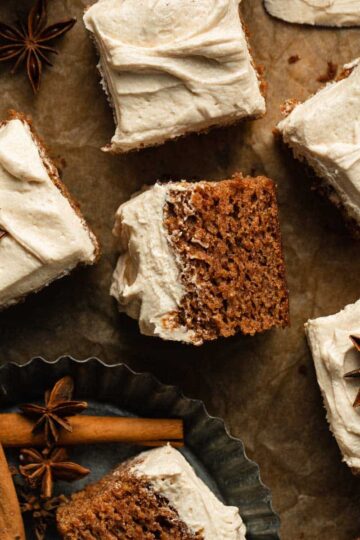 Pieces of apple spice cake with buttercream frosting arranged on a sheet of brown parchment paper.