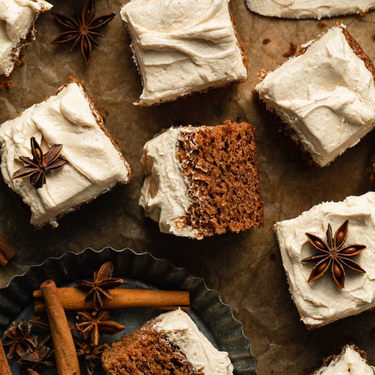 Pieces of apple spice cake with buttercream frosting arranged on a sheet of brown parchment paper.