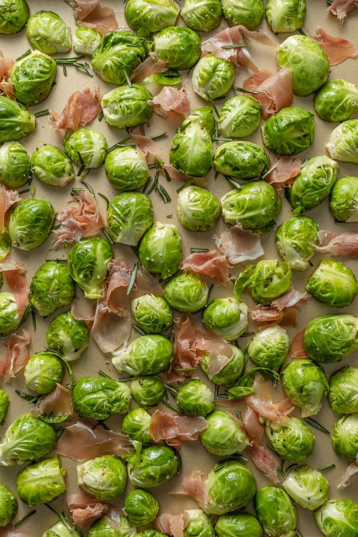 Brussels sprouts and prosciutto arranged in a single layer on a baking sheet.