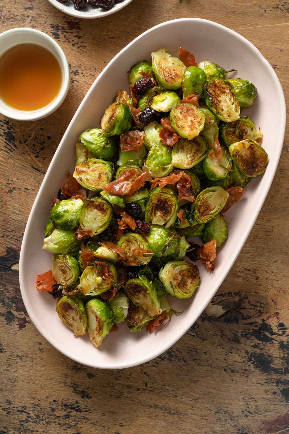 Prosciutto Brussels sprouts tossed with maple syrup and dried cranberries in a serving dish.