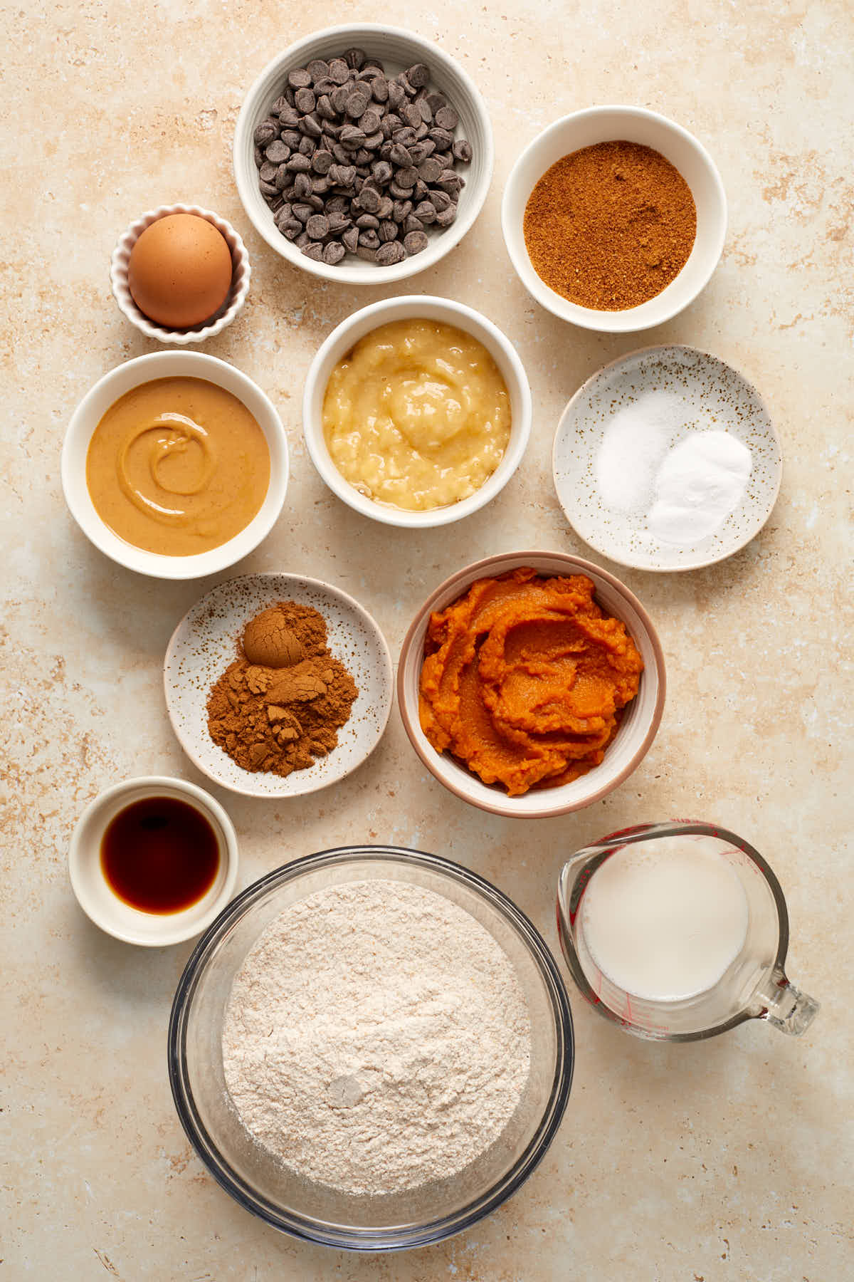 Ingredients to make pumpkin banana muffins arranged in individual dishes.