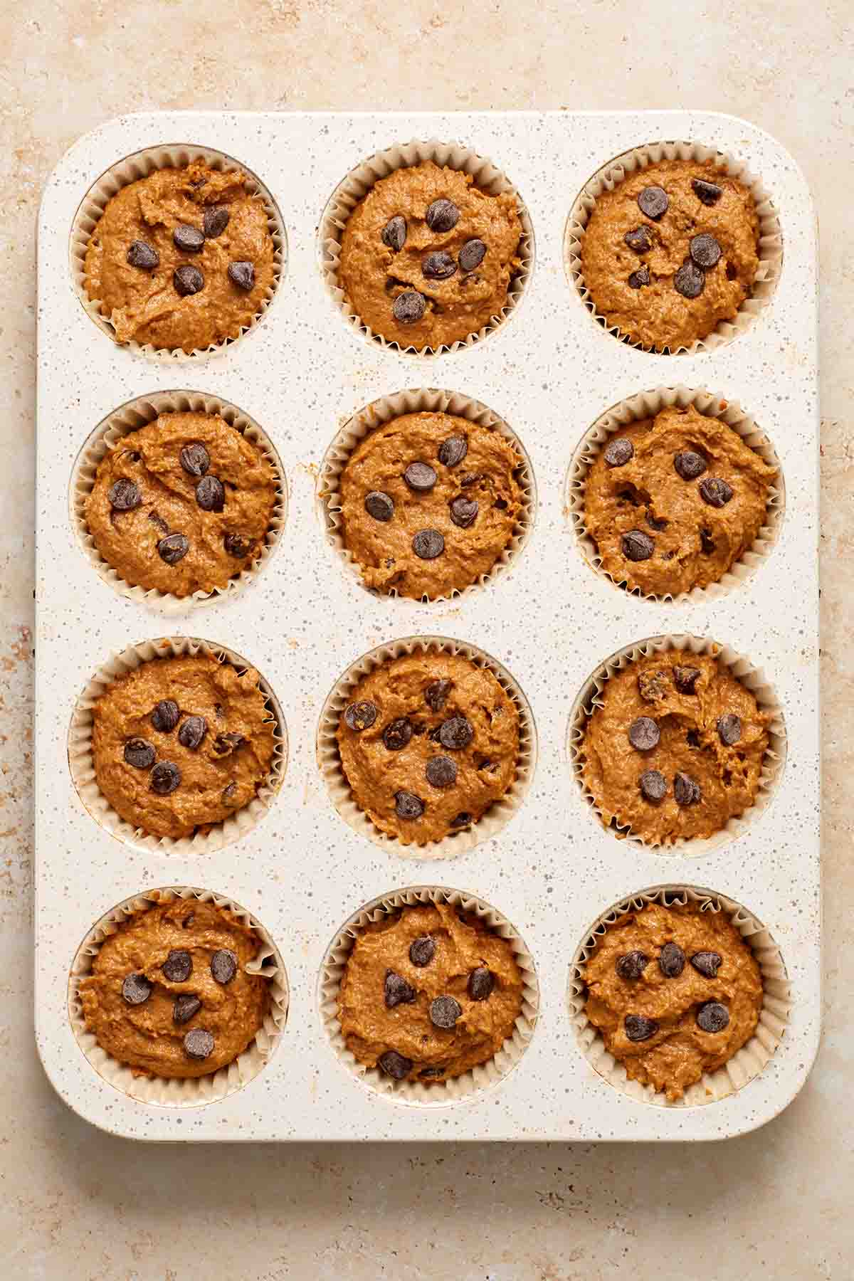 Muffin batter divided into a 12-cup muffin tin.