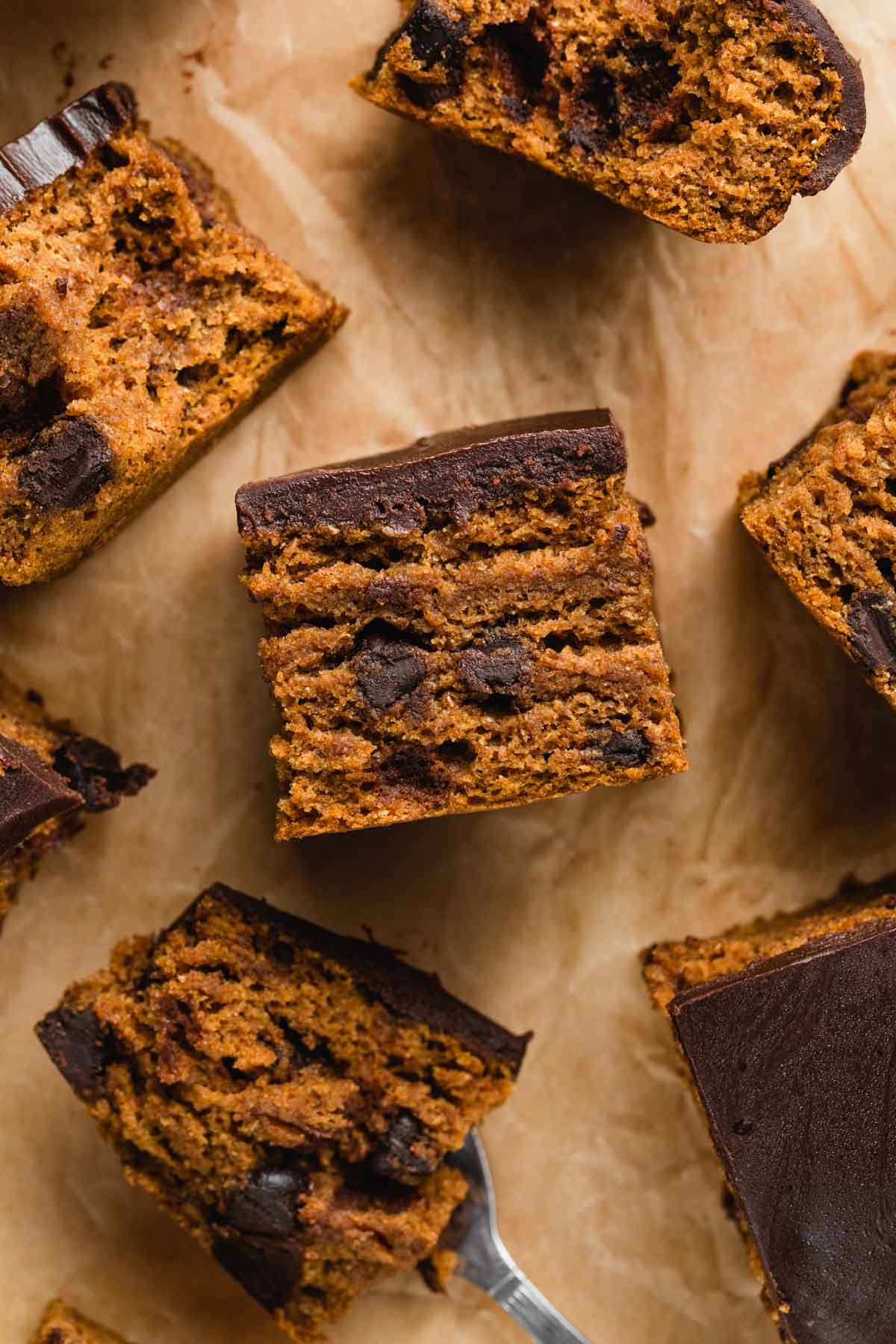Close up view of a piece of pumpkin snack cake with chocolate chips and ganache on top.