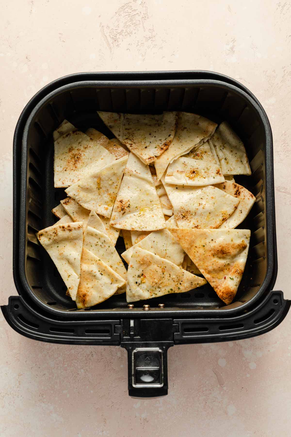 Pitas cut into triangles and placed in an air fryer basket.