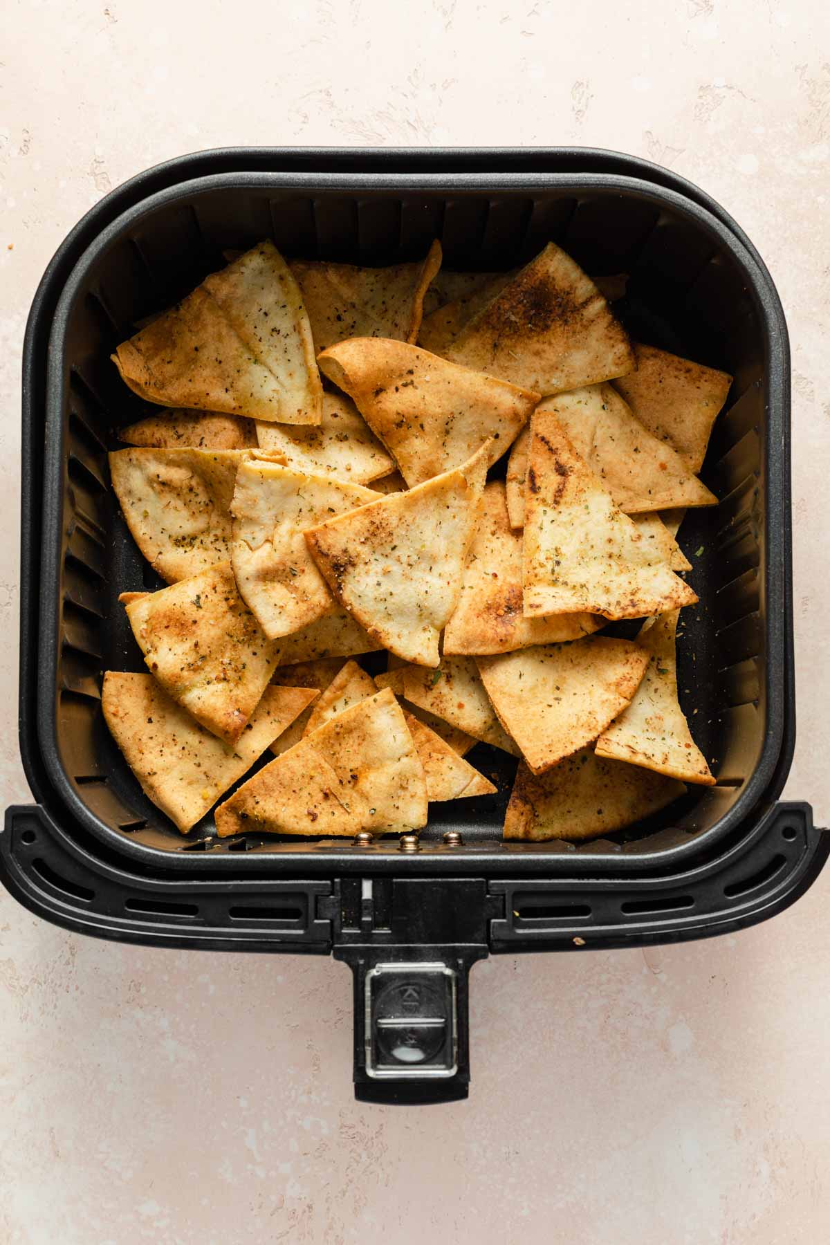 Pita chips in an air fryer basket.