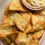 Air fryer pita chips on a platter with a side of dip.