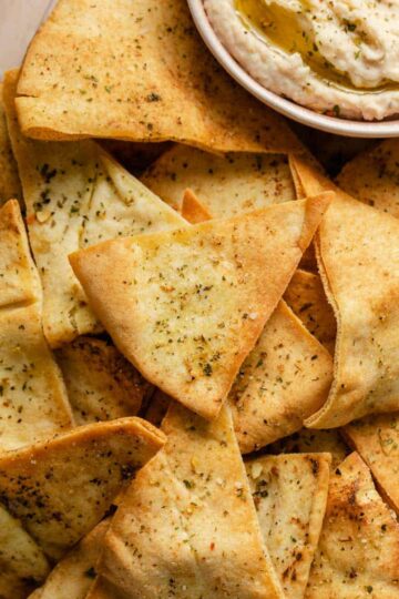 Air fryer pita chips on a platter with a side of dip.