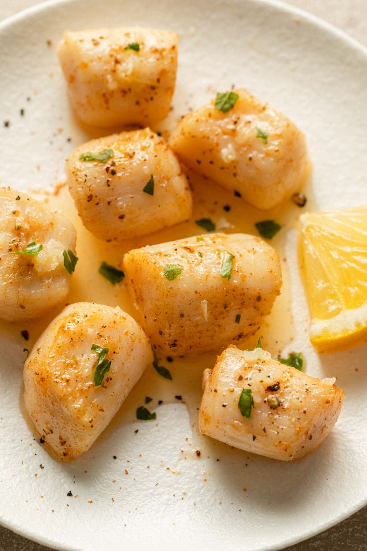 Up close view of air fried scallops topped with melted butter and chopped parsley.