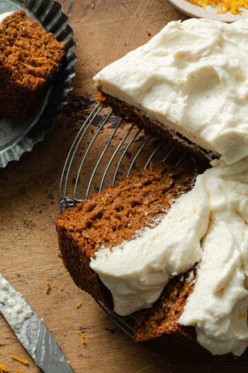 Overhead view of slices of orange spice cake with cream cheese frosting on a round cooling rack.