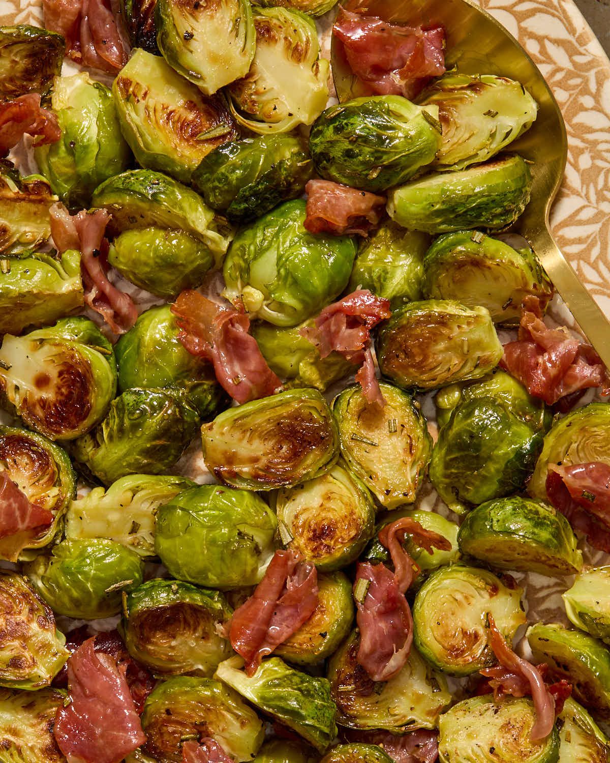Close up of Brussels sprouts and crispy prosciutto on a platter.