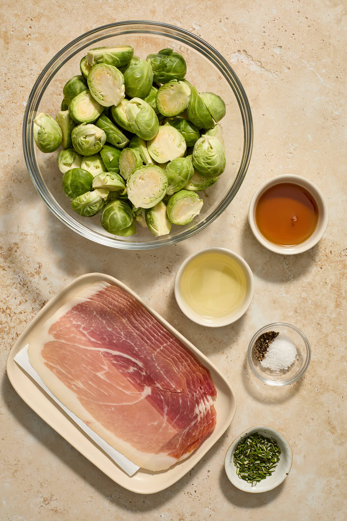 Ingredients to make roasted Brussels sprouts with prosciutto arranged in individual dishes.
