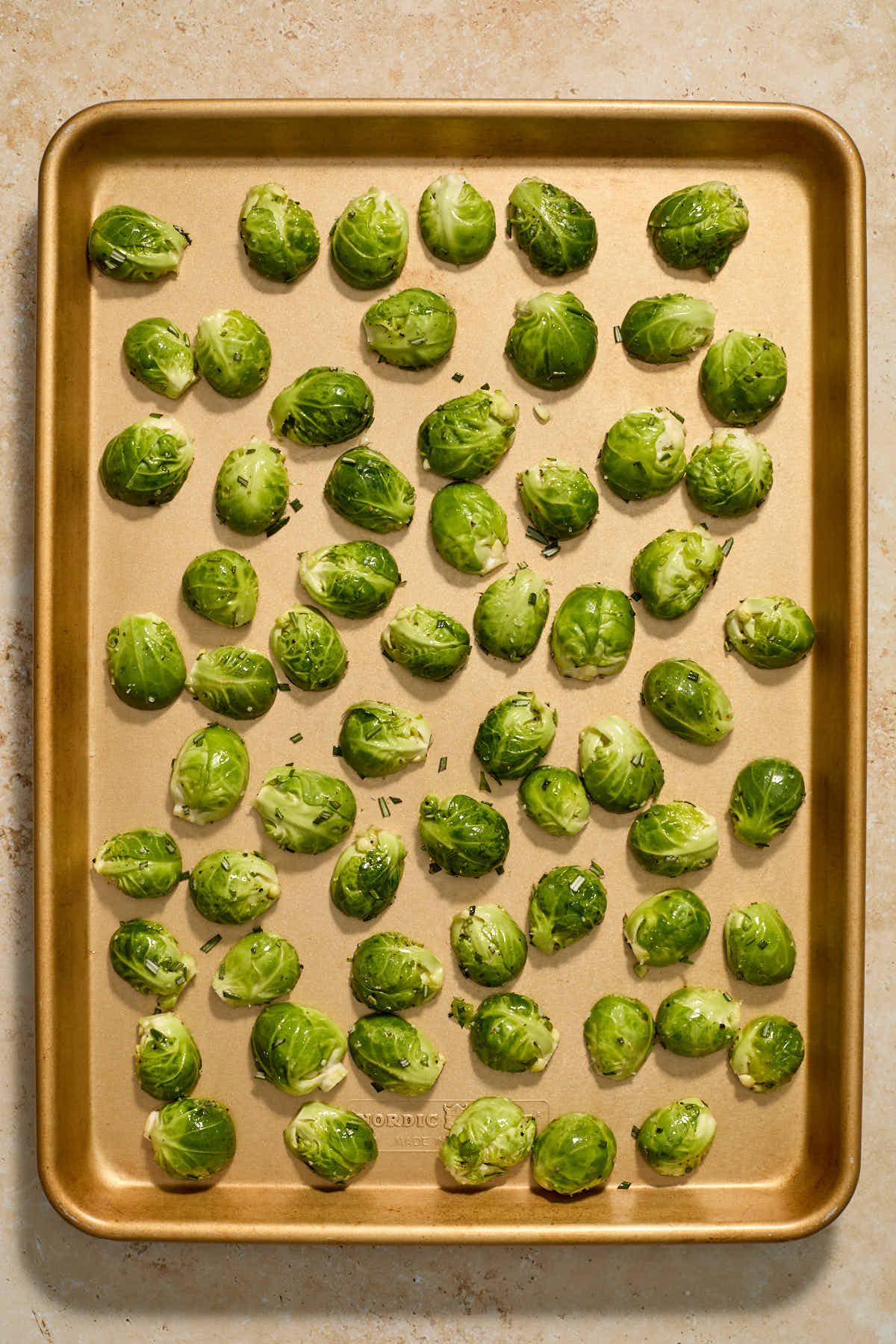 Brussels sprouts arranged cut side down on a large sheet pan.