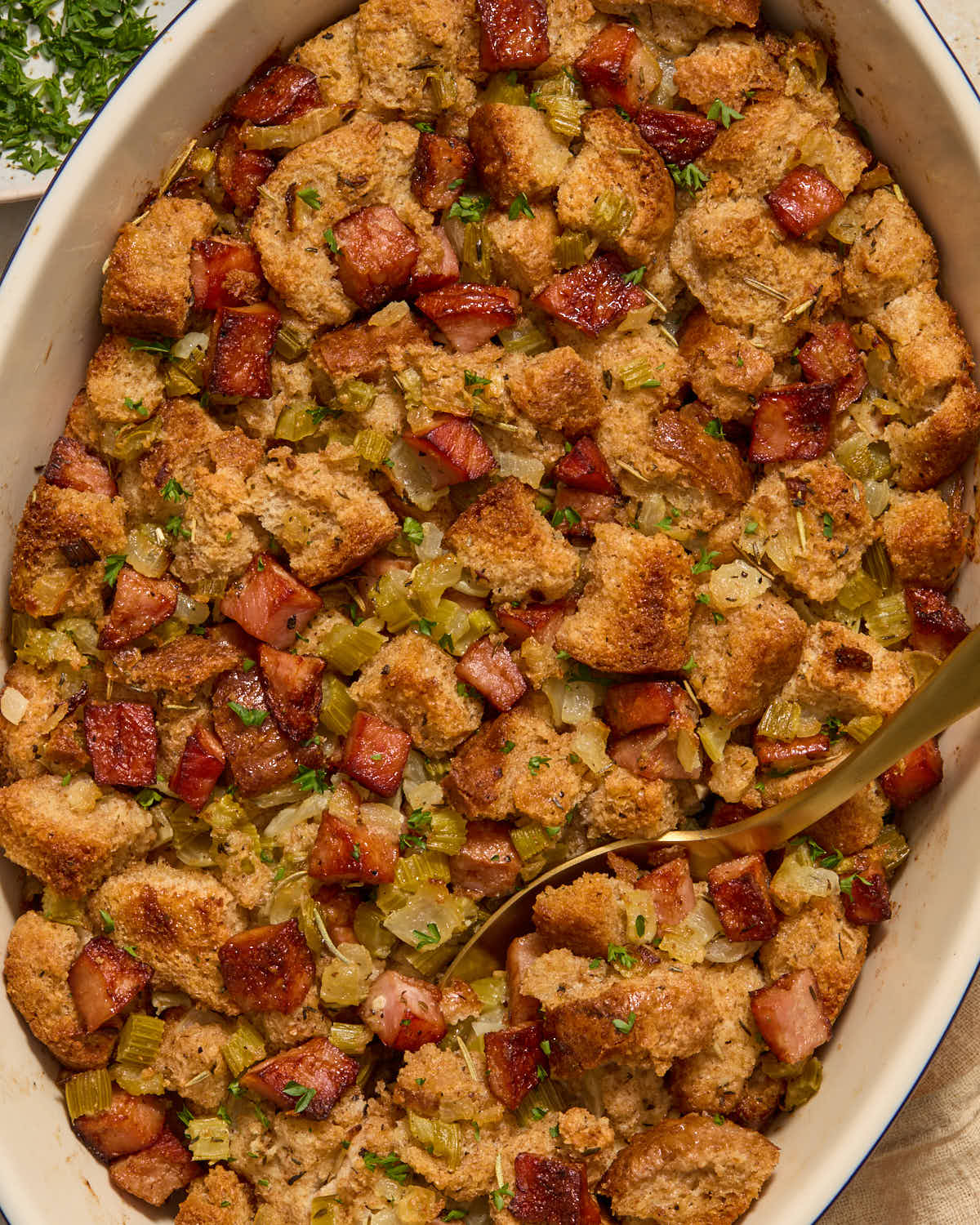 Stuffing in a dish, garnished with chopped parsley and a serving spoon inserted into it.