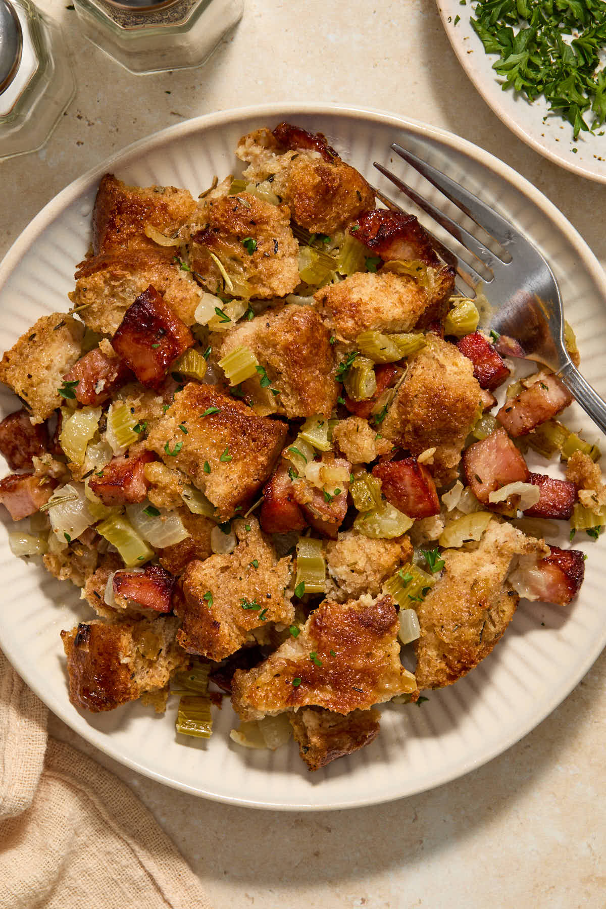 Close up of some stuffing served on a plate with a fork.