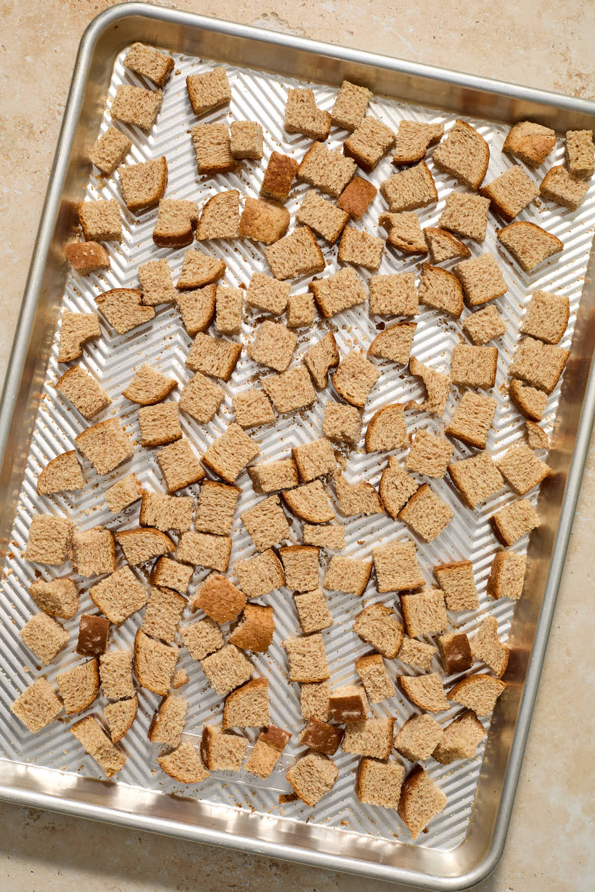 Whole wheat bread cubes toasted on a sheet pan.