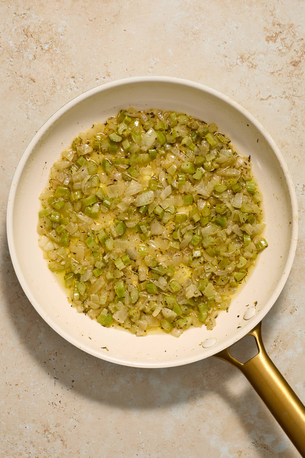 Vegetables and herbs cooked in butter in a skillet.