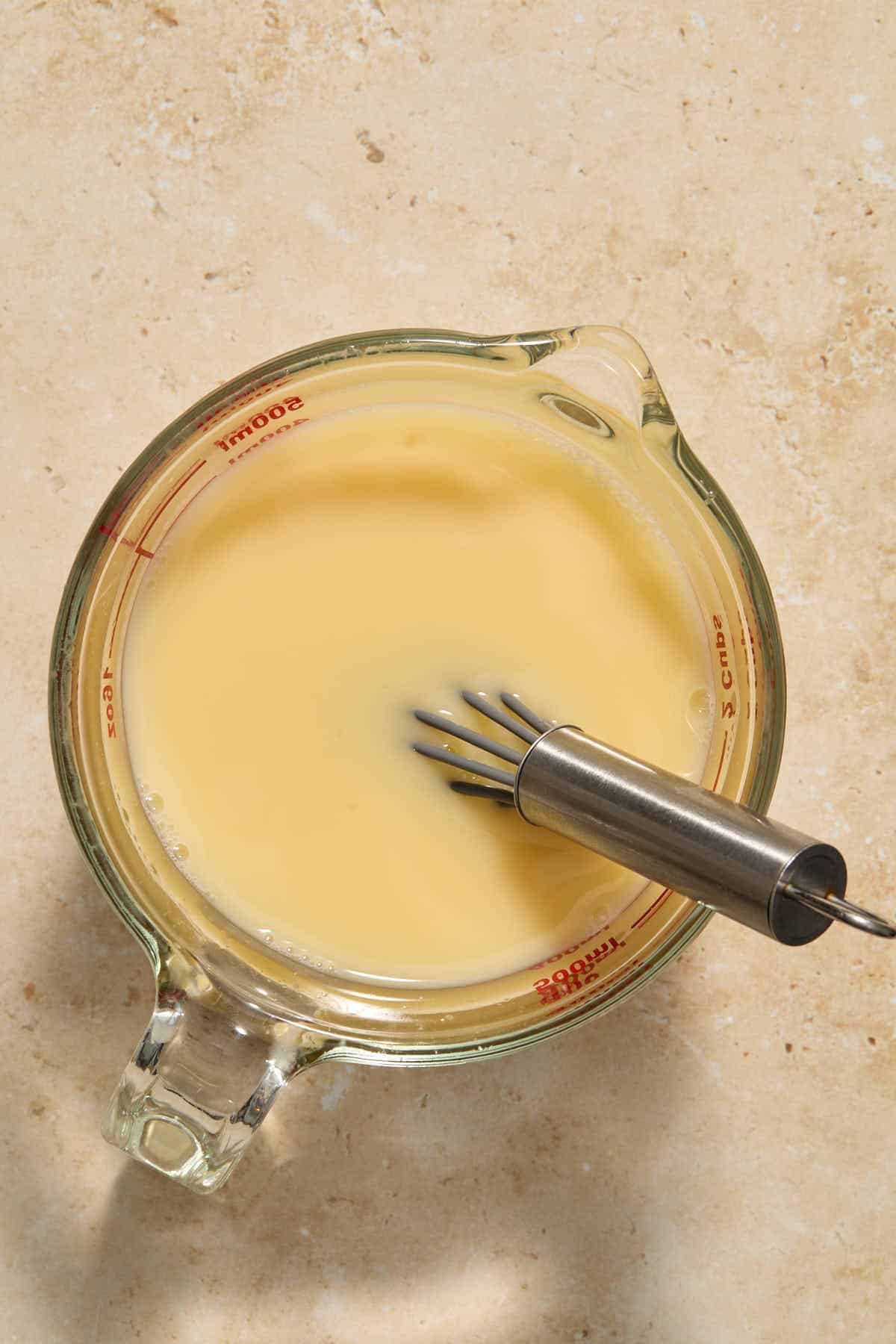 Eggs and broth whisked together in a measuring cup.