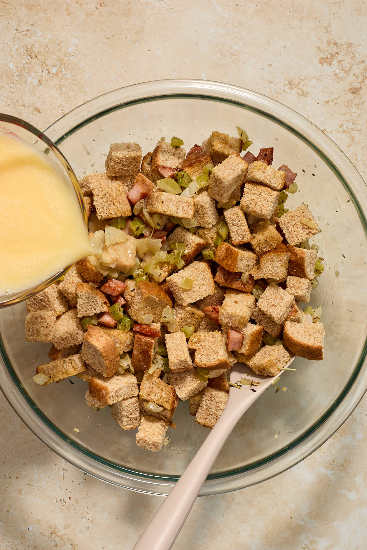 Milk/broth mixture being poured over the bread cube mixture.