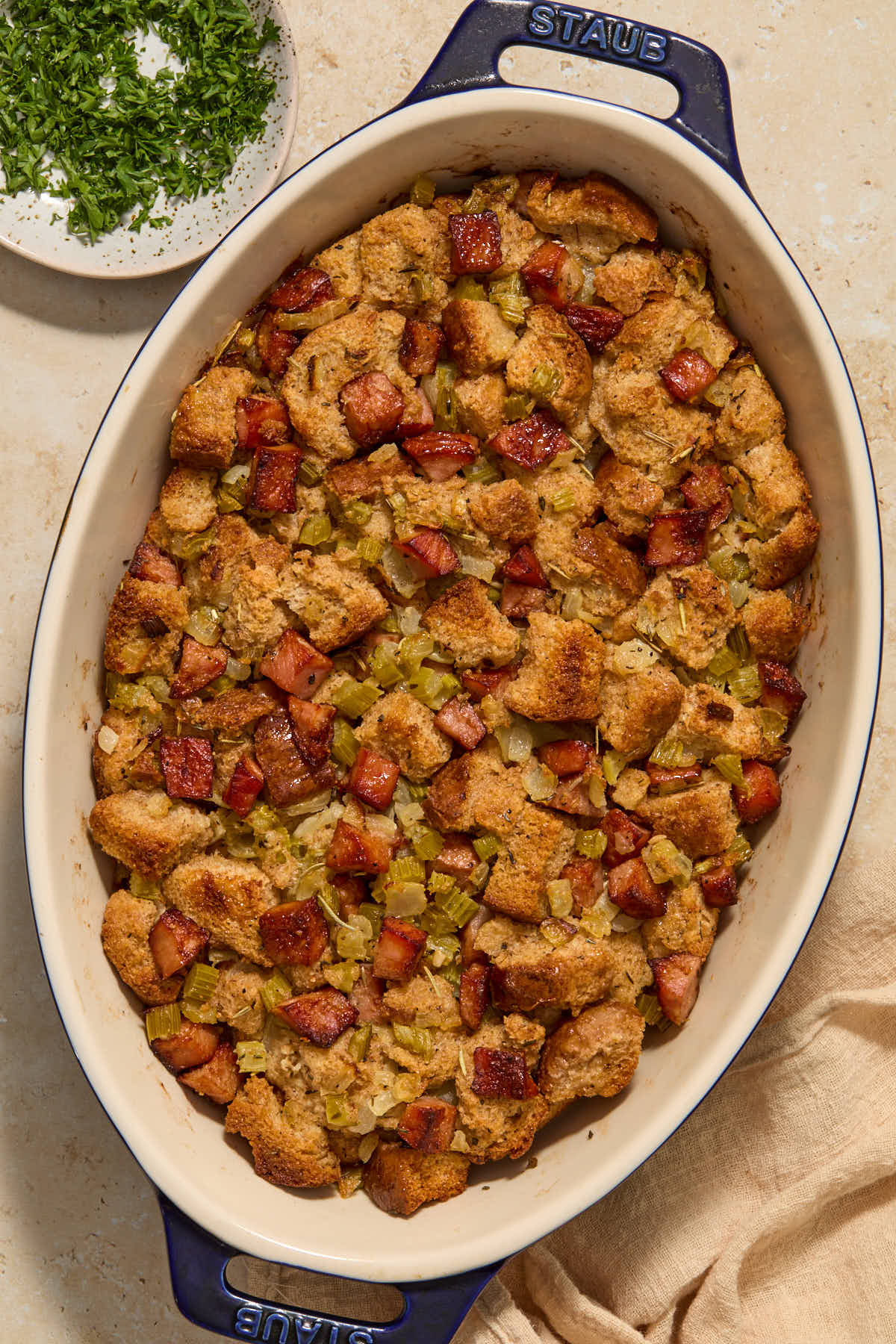 Baked stuffing in a dish with chopped parsley on the side.