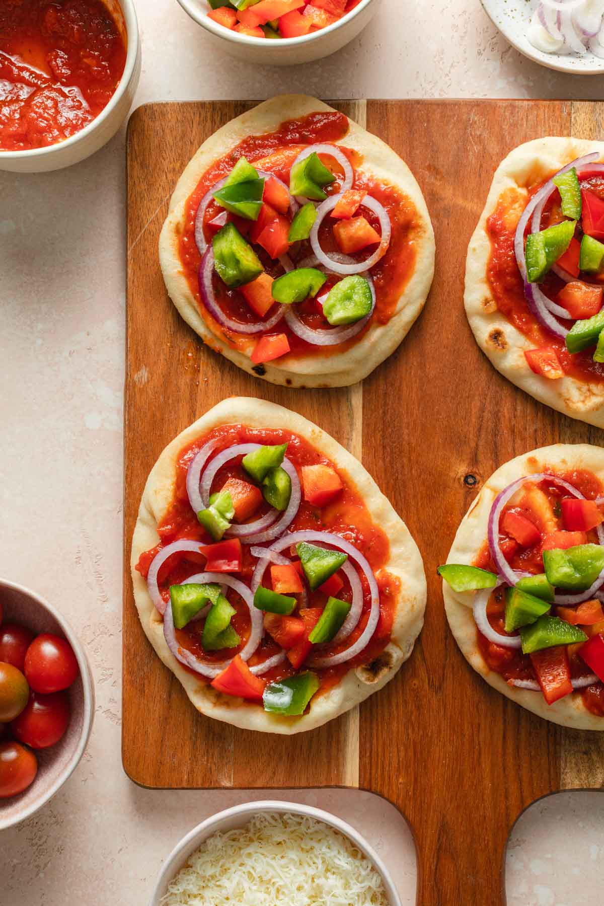 Naan bread mini pizzas with veggies arranged on top.