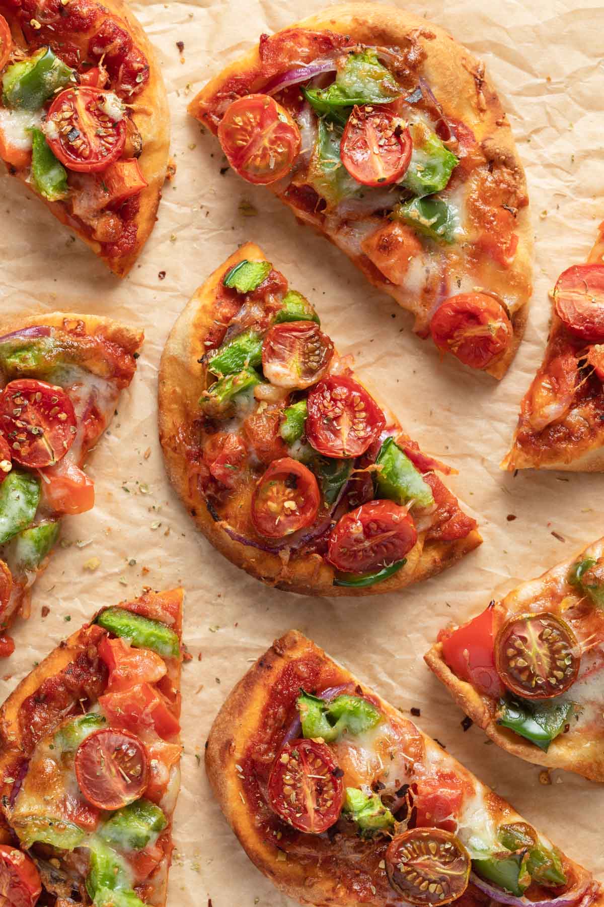 Air fryer mini pizzas made with naan bread and arranged on a sheet of parchment paper.