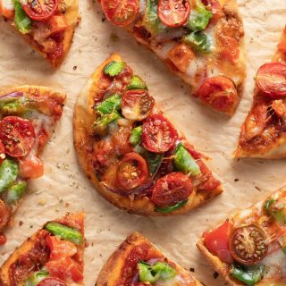 Overhead view of naan bread air fryer mini pizzas cut into pieces and arranged on parchment paper.