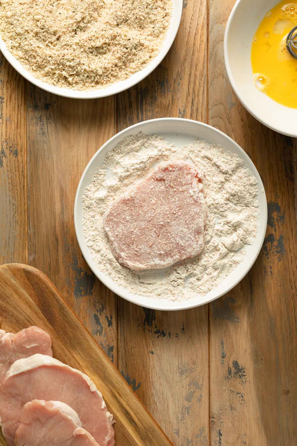 A pork cutlet coated in flour on a plate.