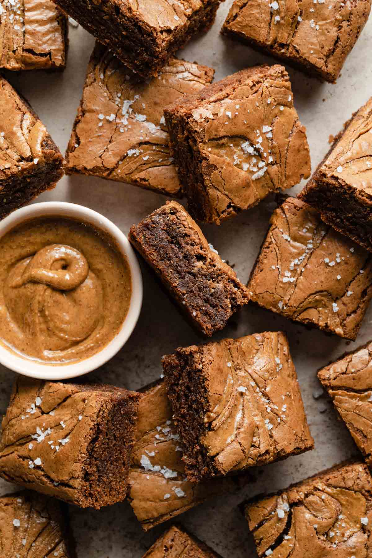 Almond butter brownies arranged around a small bowl of almond butter.