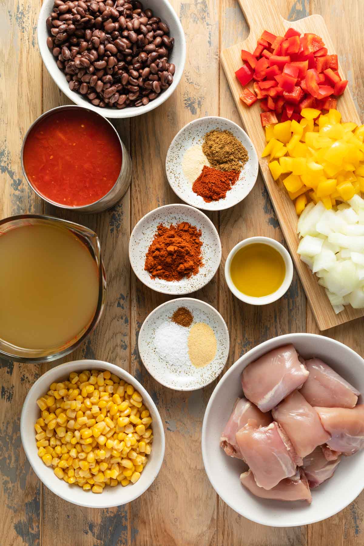 Ingredients to make chicken fajita soup arranged individually on a wooden table top.