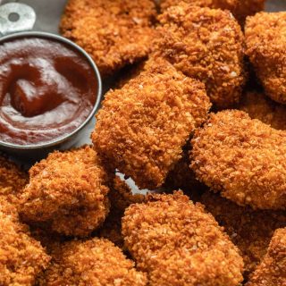 Close up view of air fryer chicken bites with dipping sauce on the side.