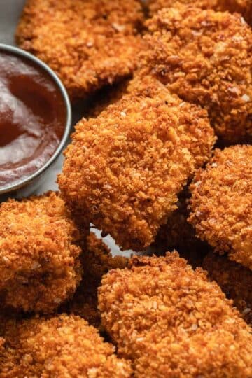 Close up view of air fryer chicken bites with dipping sauce on the side.