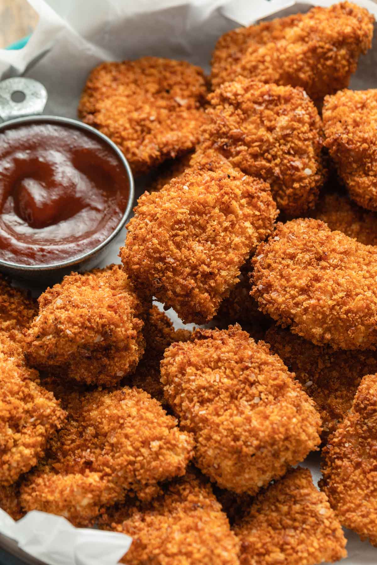 Crispy breaded chicken nuggets on a platter with BBQ for dipping.