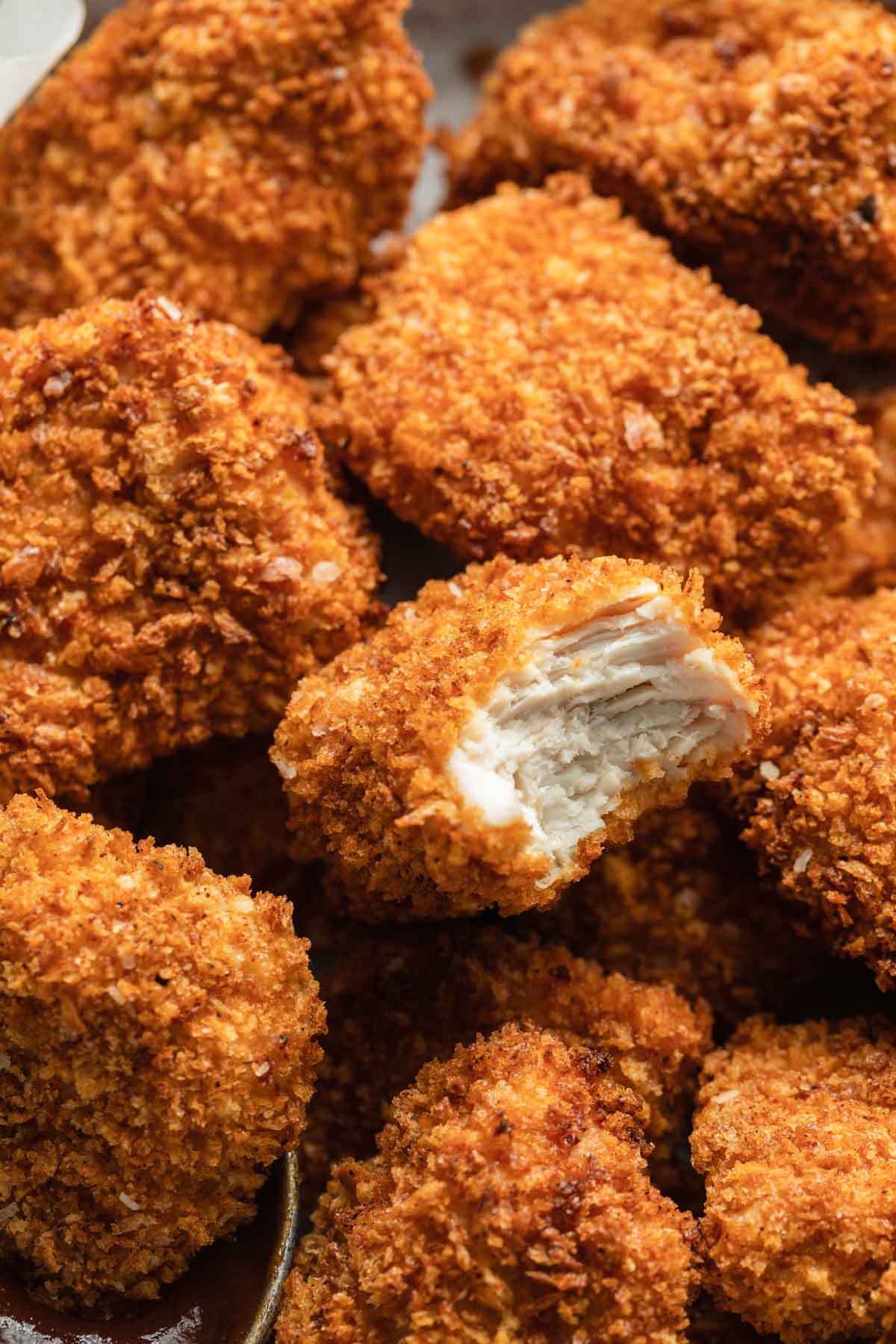 Close up view of a chicken nugget with a bite taken out of it.