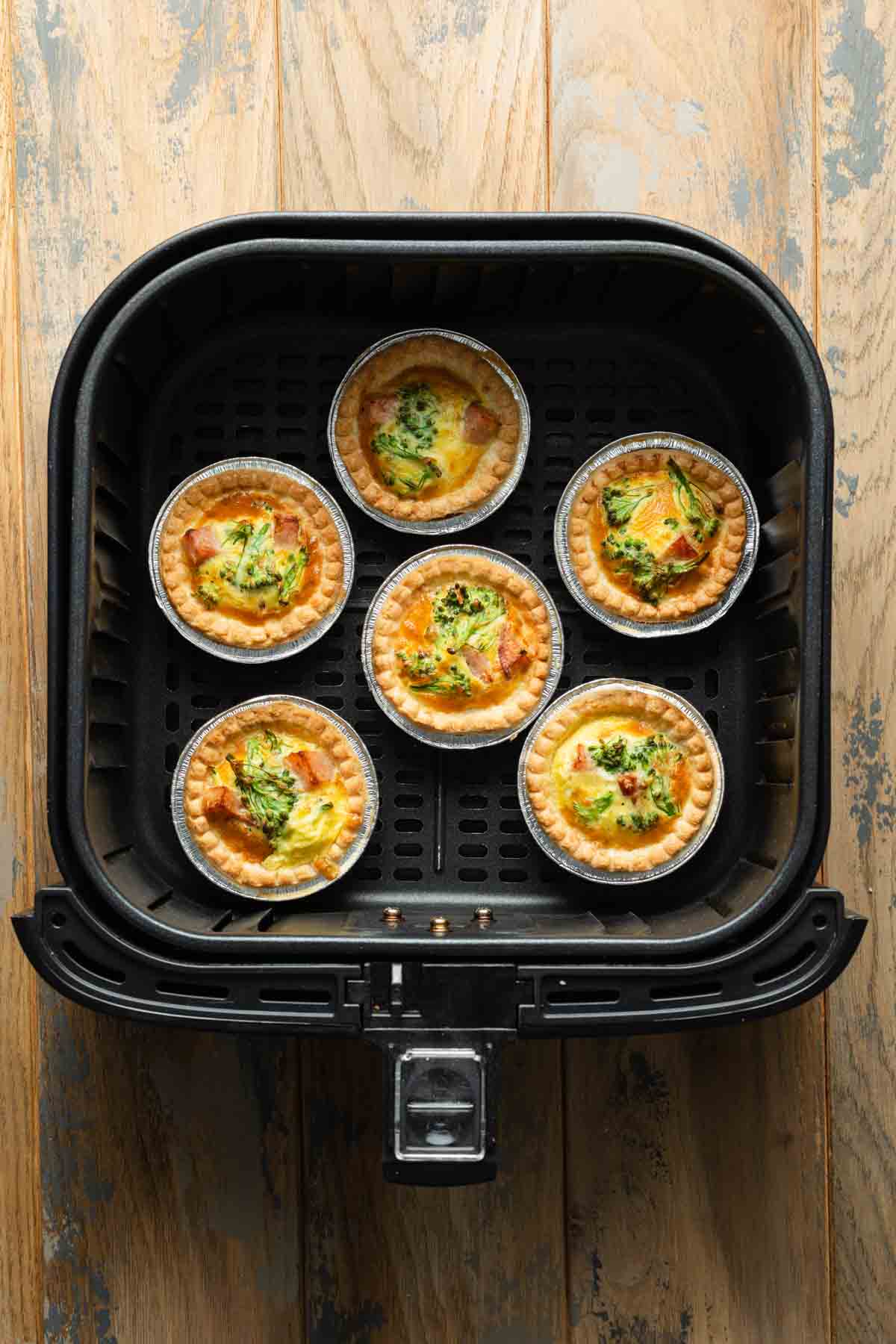 Cooked mini quiches in an air fryer basket.